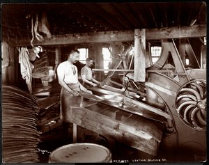 Interiørbilde av to menn som arbeider med lær og tungt utstyr ved New York Leather Belting Co., New York, 1905 (sølv gelatintrykk)